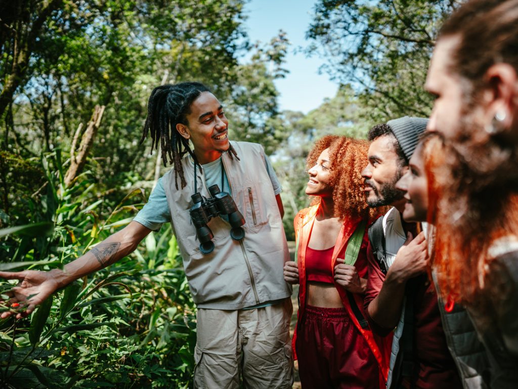 Tourist guide showing plants to a group of friends hiking in the forest - Edgewood Travel