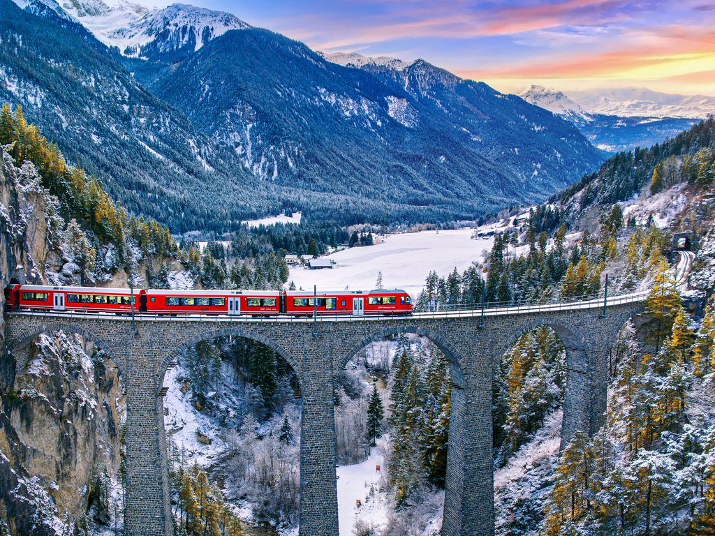 Aerial view of Train passing through famous mountain in Filisur, Switzerland. Landwasser Viaduct world heritage with train express in Swiss Alps snow winter scenery - Edgewood Travel