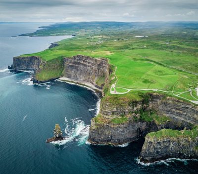 Image for Aerial view of the Cliffs of Moher in Ireland with dramatic limestone cliffs, lush green fields, and the Atlantic Ocean below.