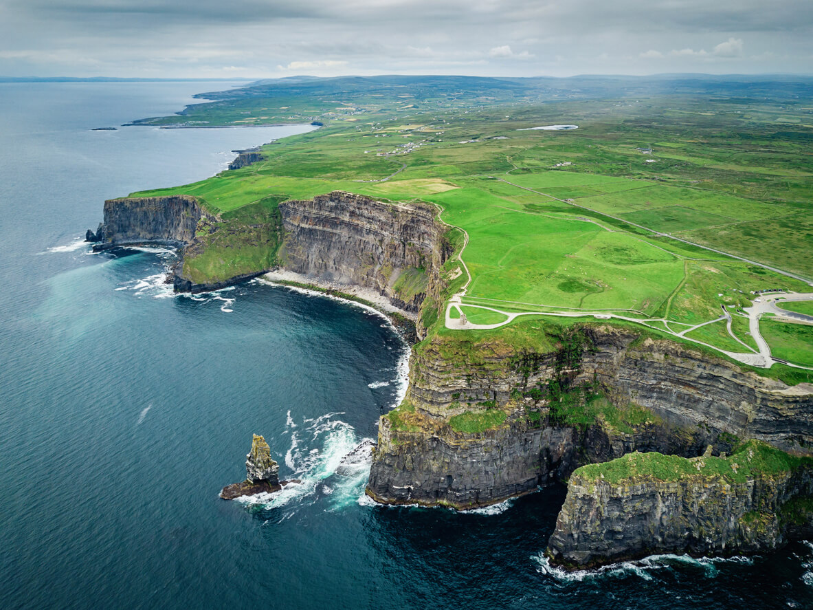 Image for Aerial view of the Cliffs of Moher in Ireland with dramatic limestone cliffs, lush green fields, and the Atlantic Ocean below.